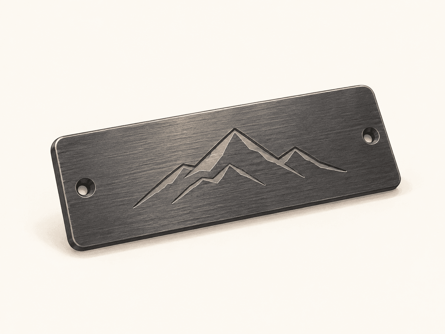 A metal nameplate engraved with a mountain range design